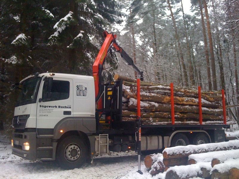 Ein Mercedes-LKW transportiert Baumstämme im Schnee