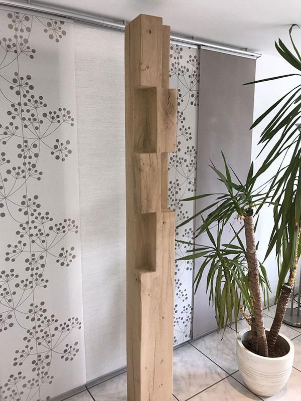 In einem Raum steht ein Holzregal neben einer Topfpflanze.