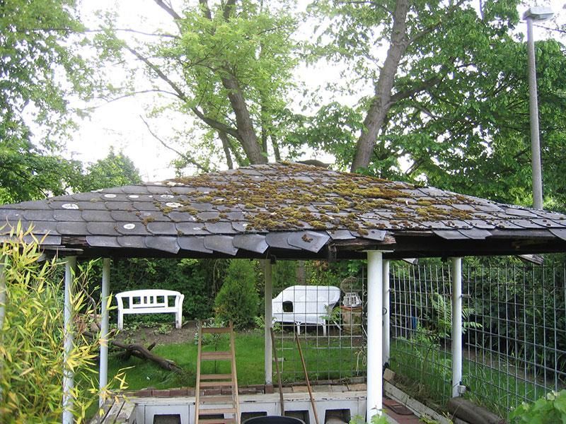 Ein Pavillon mit einem Dach, auf dem Moos liegt