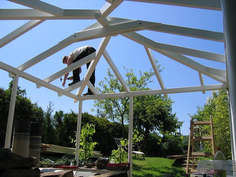Ein Mann arbeitet an einer Holzkonstruktion in einem Garten