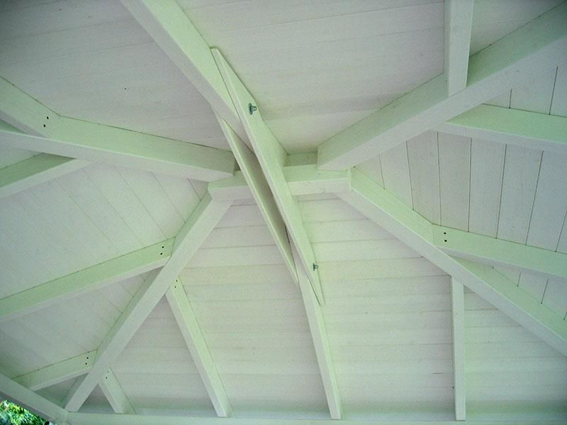 Die Decke eines Pavillons mit weißen Holzbalken.