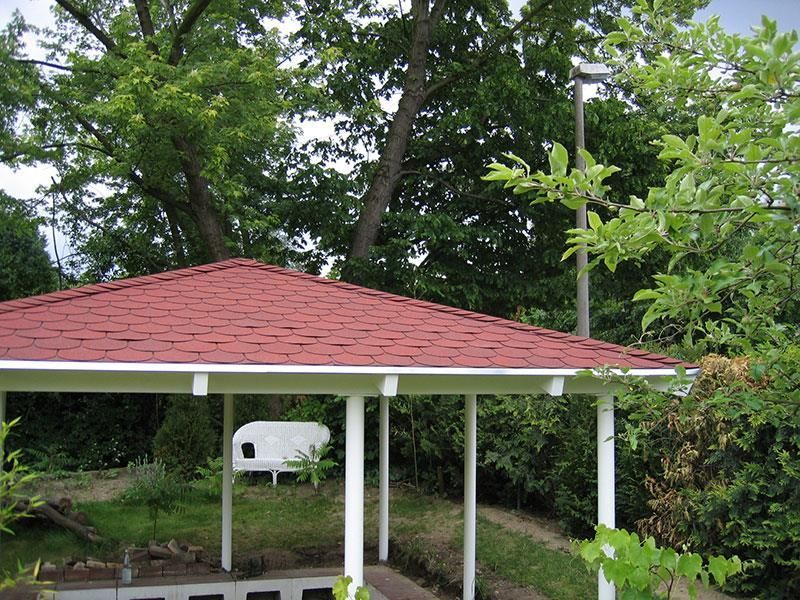 Ein Pavillon mit rotem Dach ist von Bäumen umgeben
