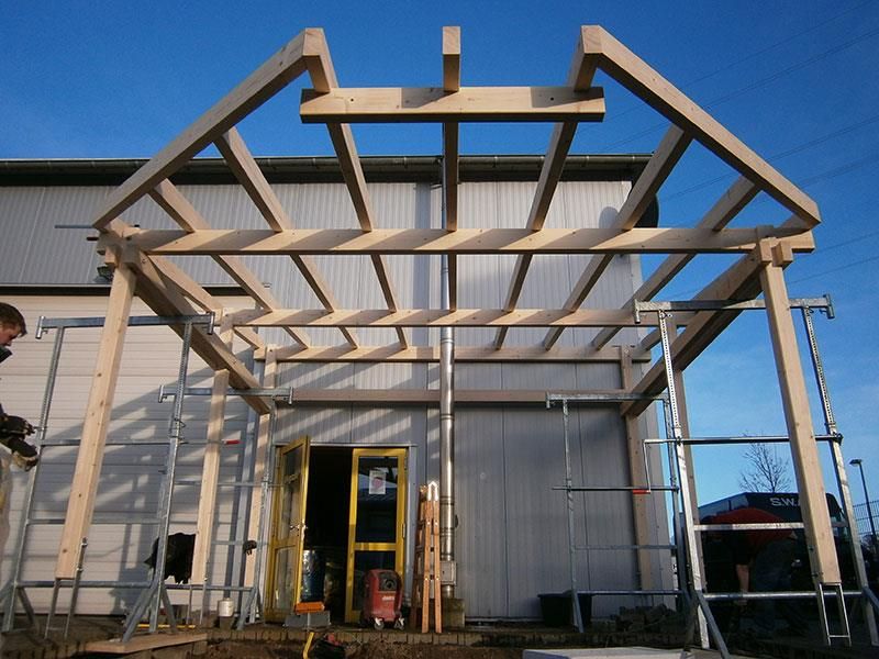 Vor einem Gebäude wird eine Holzkonstruktion errichtet