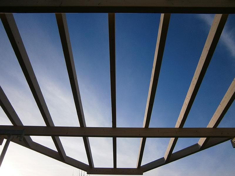 Blick nach oben in einen blauen Himmel durch eine Holzkonstruktion