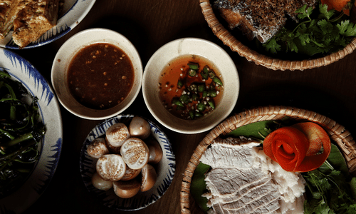 A table topped with plates of food and bowls of sauces.