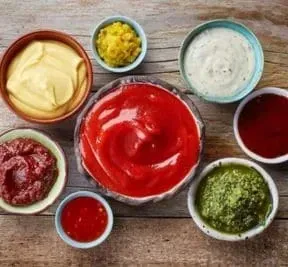There are many different types of sauces in bowls on the table.