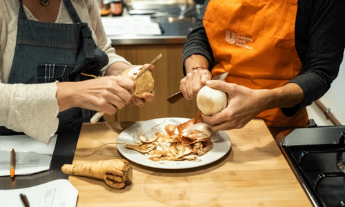 A man and a woman are peeling an onion in a kitchen.
