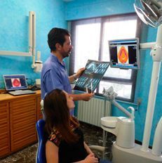 Un hombre le muestra a una mujer una radiografía en un consultorio dental.