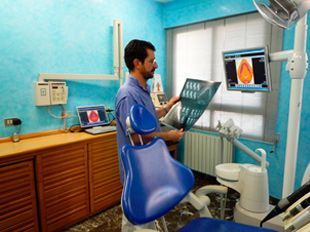 Un hombre está sentado en una silla dental mirando una radiografía.