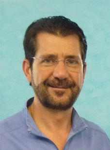 Un hombre con barba y gafas sonríe para la cámara.