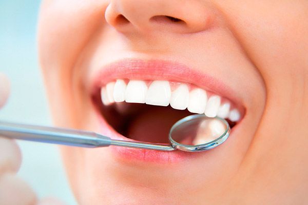 Una mujer está siendo examinada por un dentista.