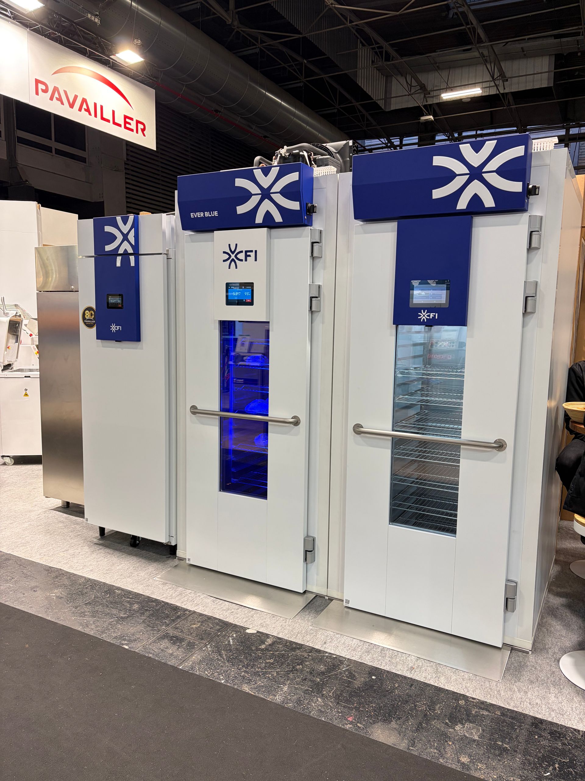 Unités de réfrigération industrielle blanches et bleues, portant l'inscription FI et dotées d'écrans lumineux, dans un contexte de salon professionnel.