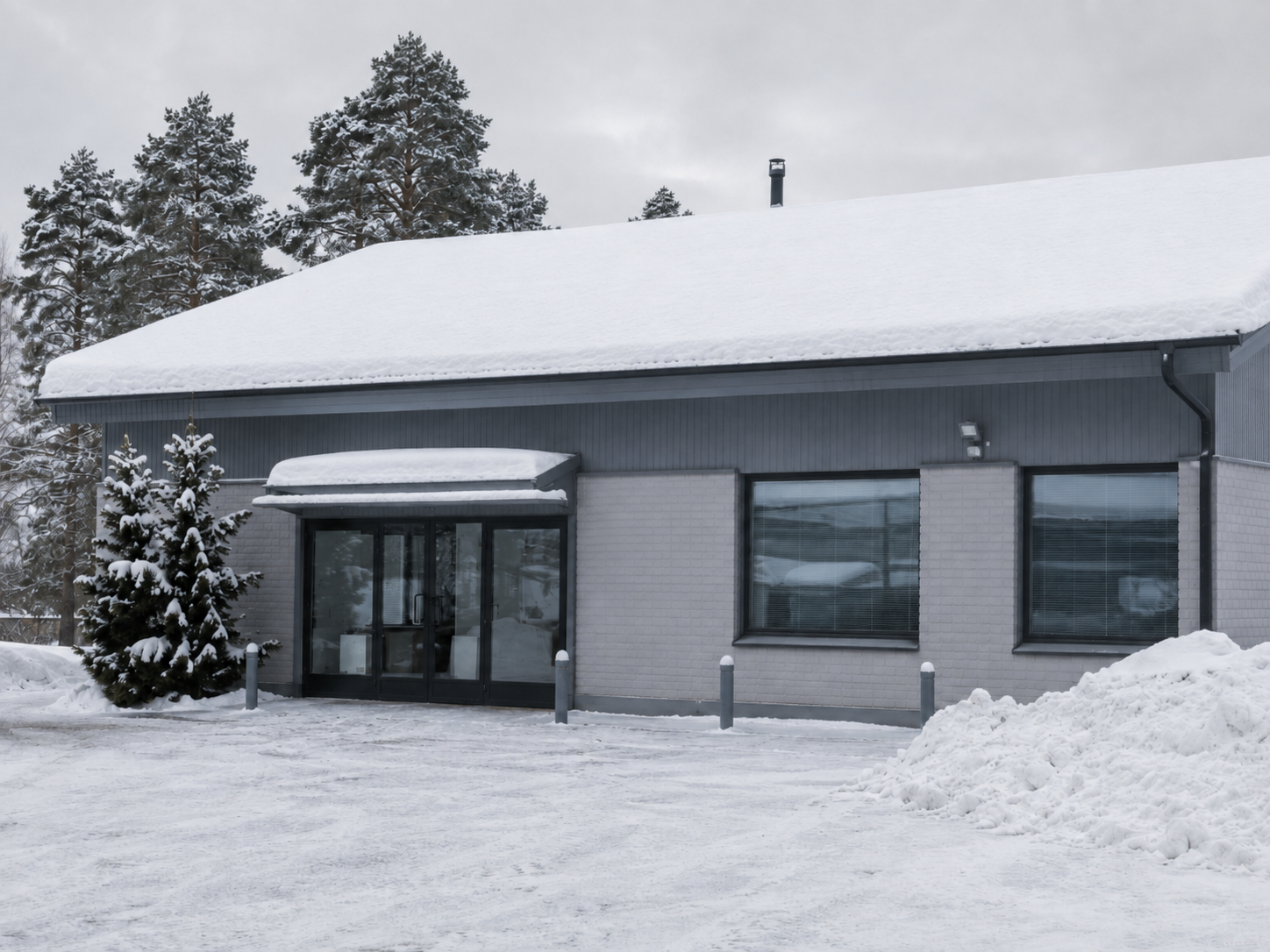 Lumikuorman peittämä pienen liikekiinteistön katto talvella