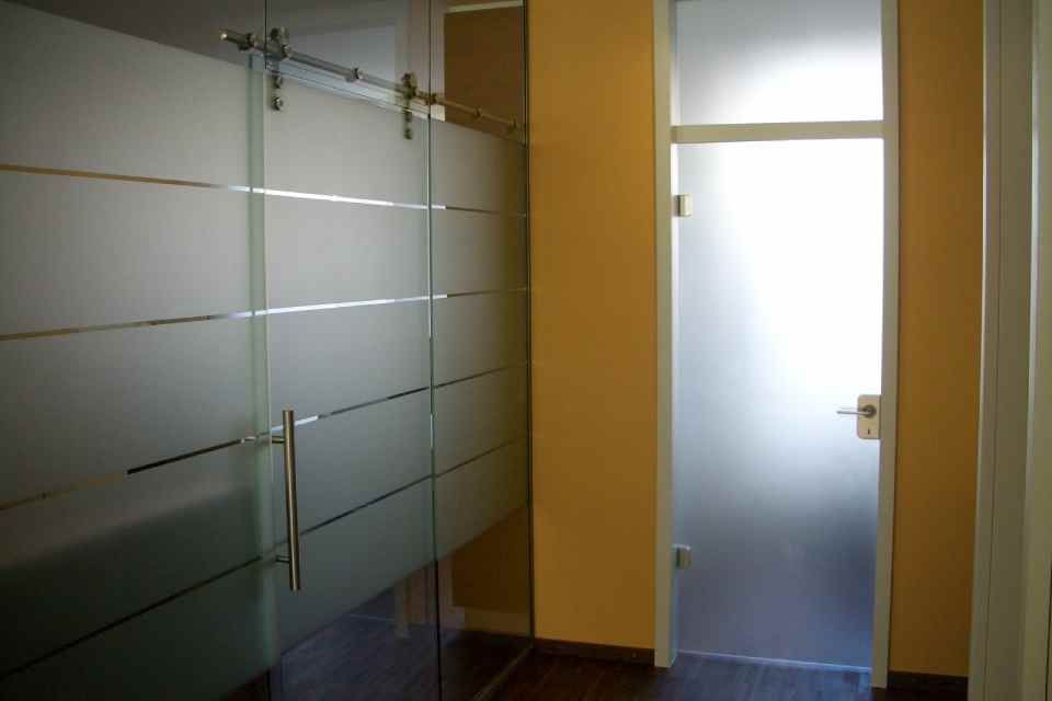 Milchglastüren im Flur, einige davon Schiebetüren. Goldene Wände, dunkler Boden und ein heller Inneneingang.