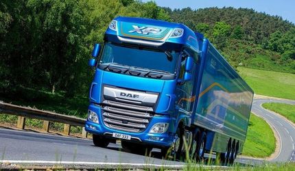 Un camión azul circula por una carretera con curvas.