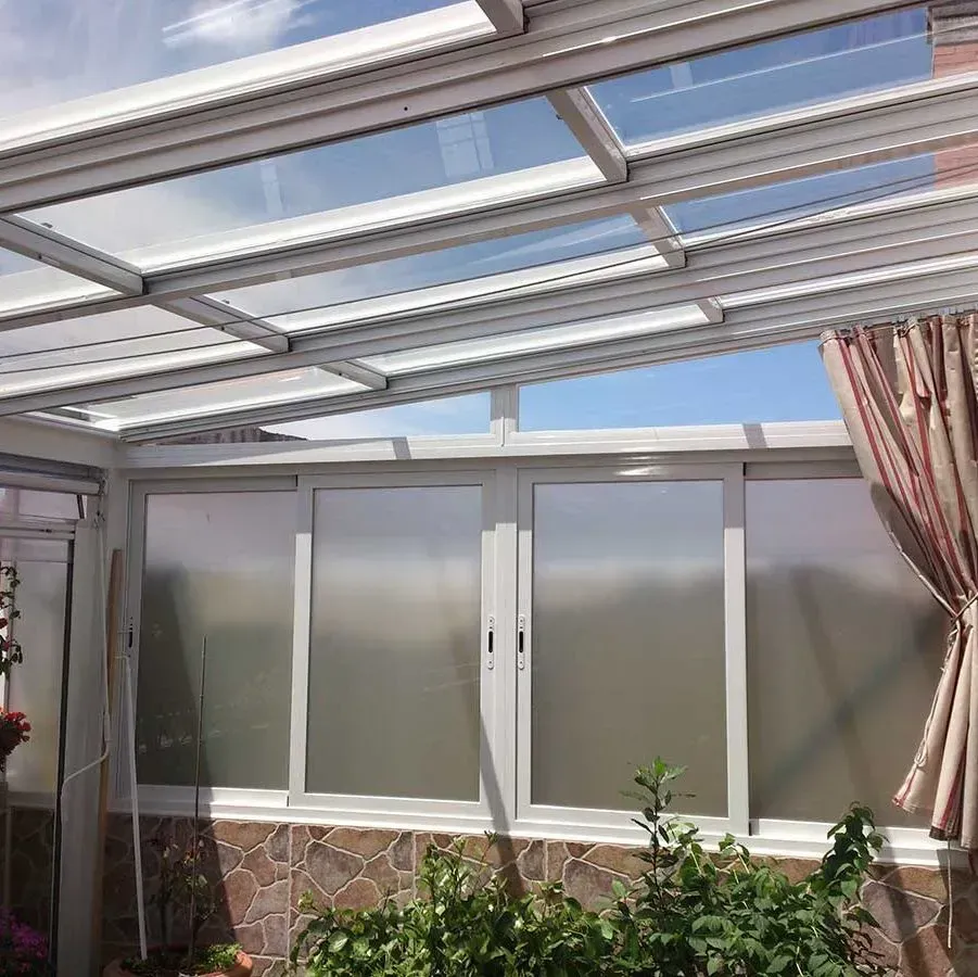 Terraza acristalada con techo transparente y ventanas esmeriladas que dejan ver el cielo.