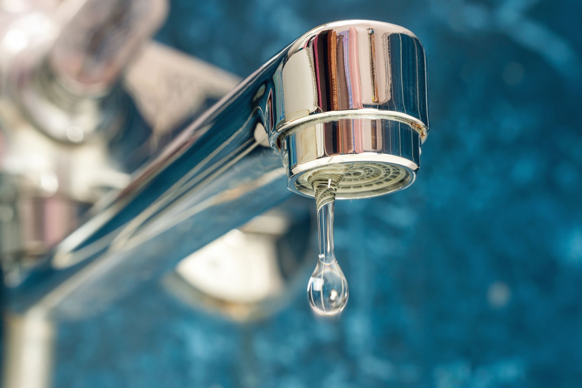 Une goutte d'eau sortant d'un mitigeur : fuite d'eau
