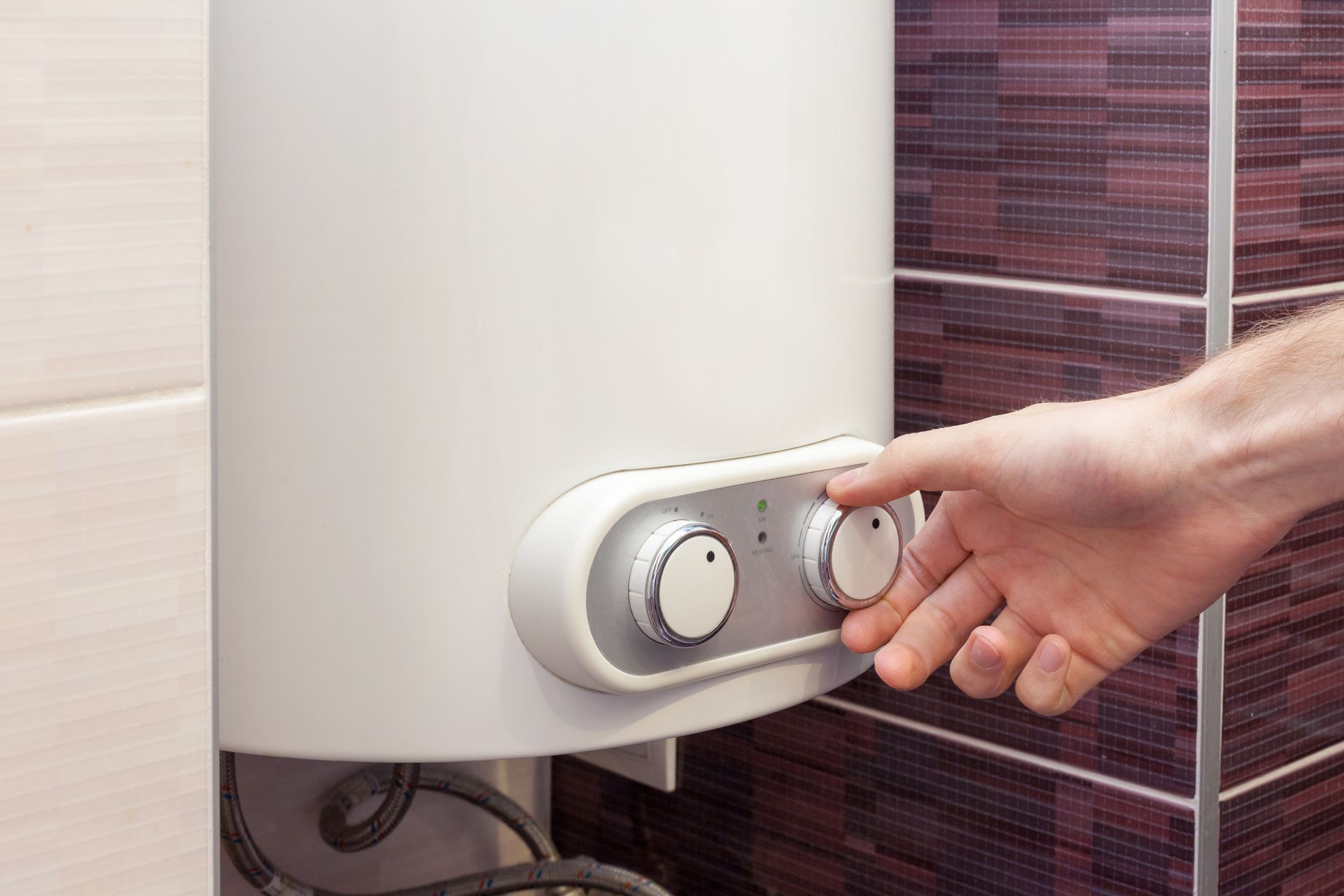Une personne qui tourne le bouton d'un chauffe-eau
