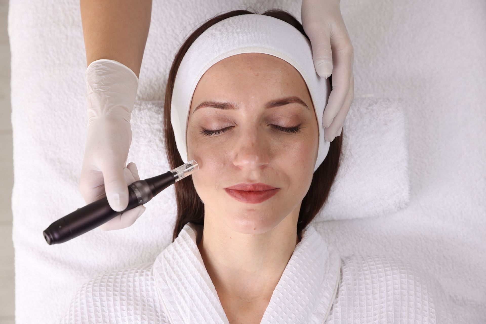 Mujer recibiendo tratamiento facial, con manos enguantadas y utilizando un dispositivo en su mejilla.