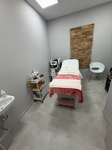 Una sala de tratamientos de spa con mesa de masajes, equipo médico y un pequeño lavabo.