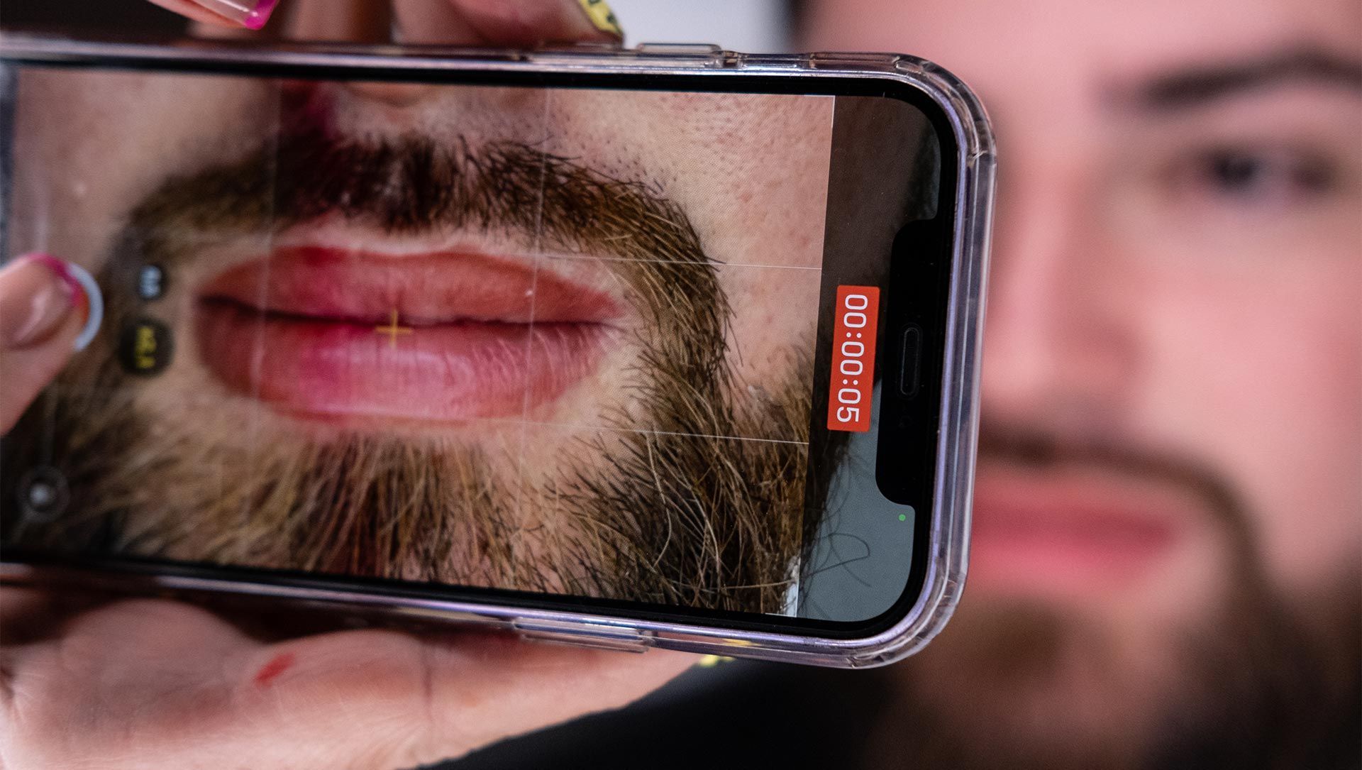 Un hombre con barba se está tomando una foto con un teléfono celular.