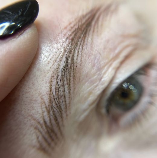 Un primer plano del ojo de una mujer con esmalte de uñas negro.
