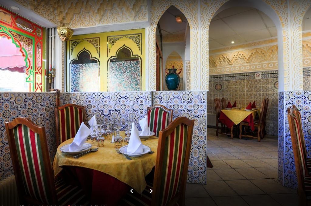 Intérieur d'un restaurant marocain au décor orné, avec des tables dressées pour le repas.