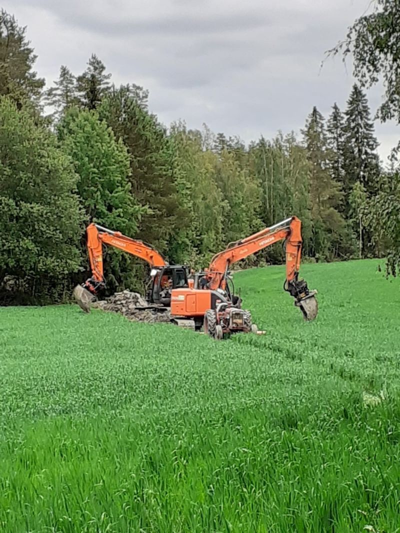 Kaksi kaivinkonetta pellolla