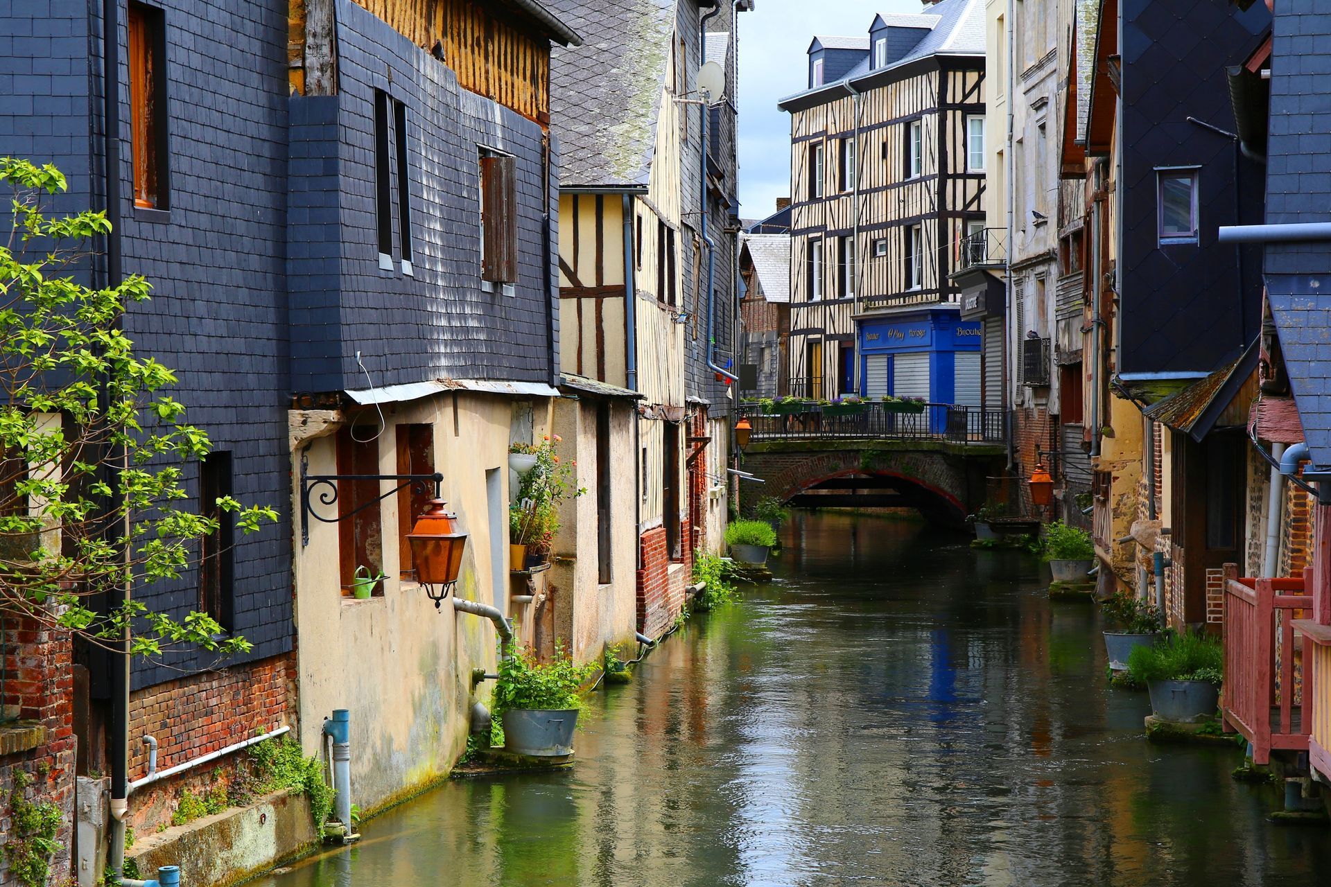 Canal bordé de bâtiments historiques, certains à colombages, sous un ciel nuageux.
