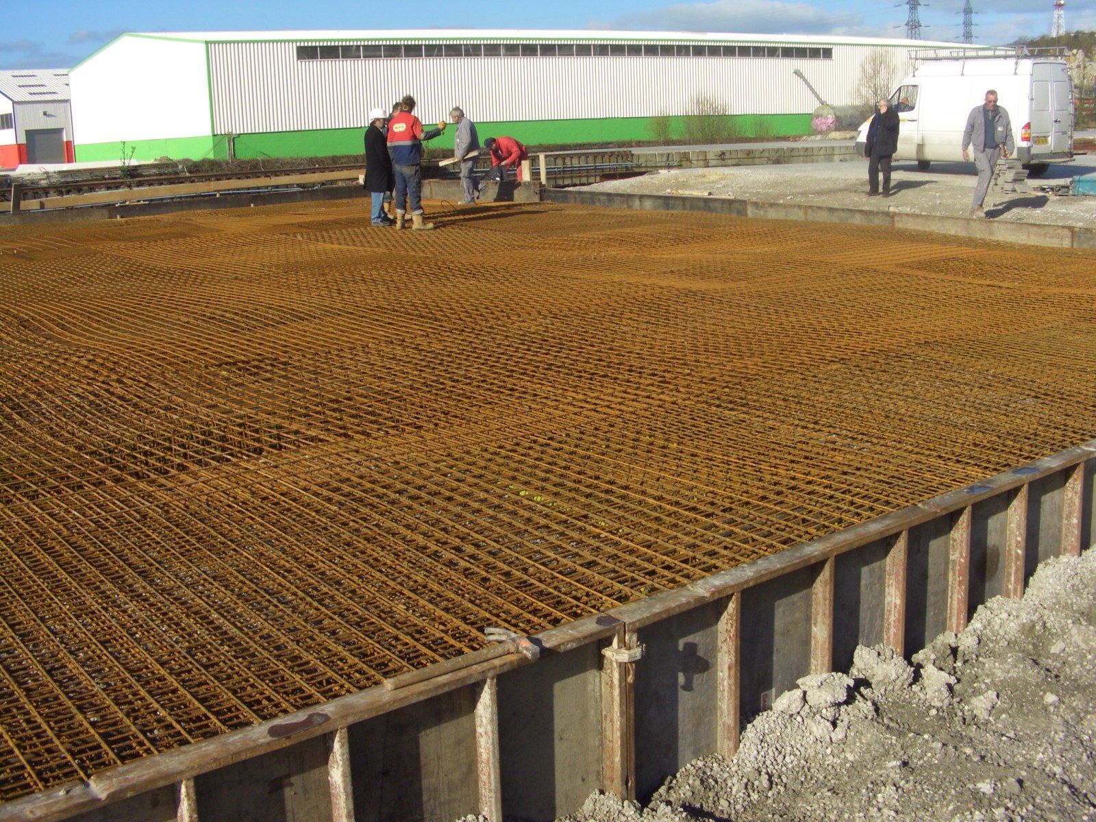 Des ouvriers construisent une fondation en béton armé d'une armature rouillée. Chantier extérieur.