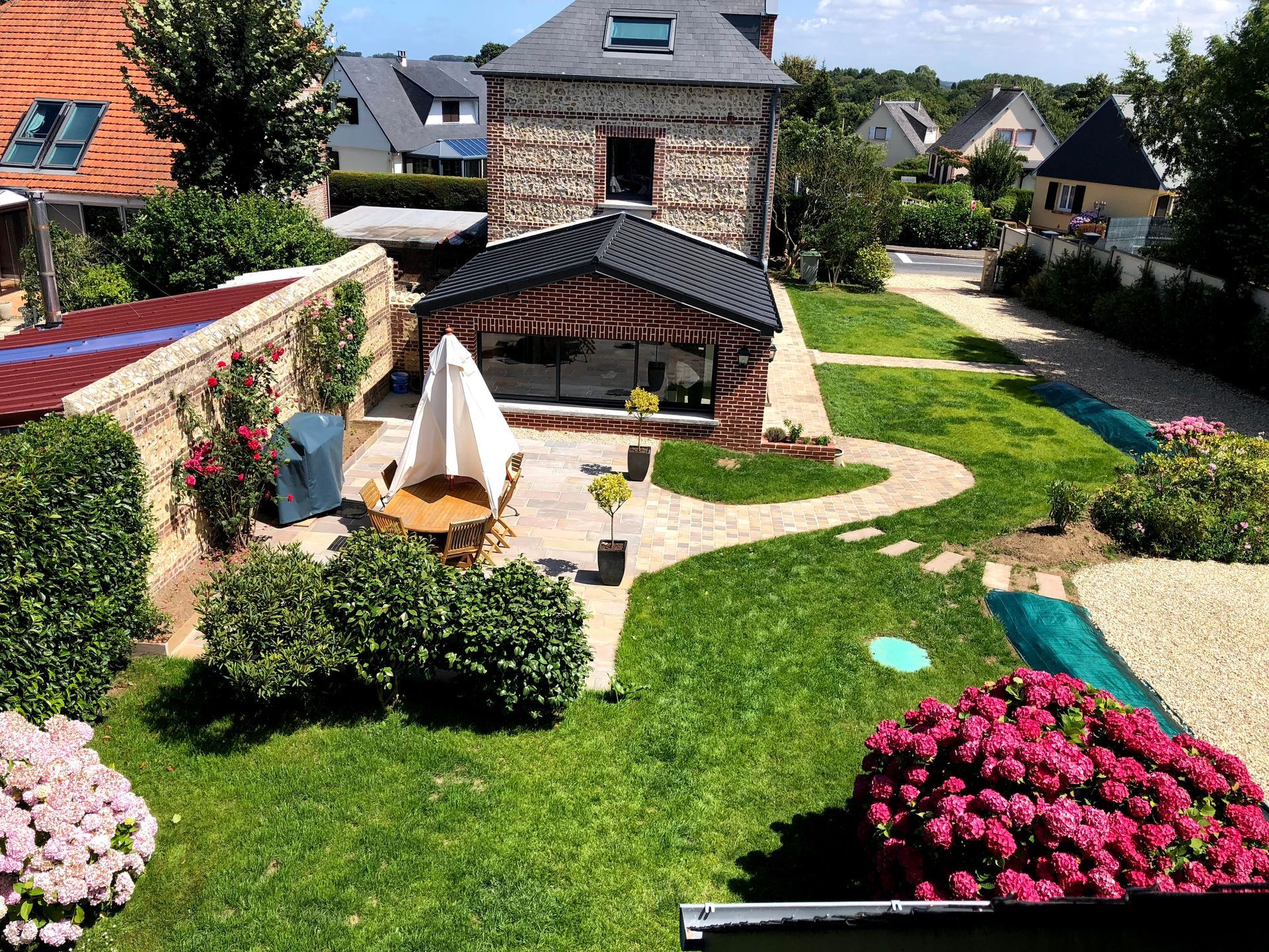 Travaux de construction d'une terrasse en cours près d'une maison à colombages ; un ouvrier est visible.