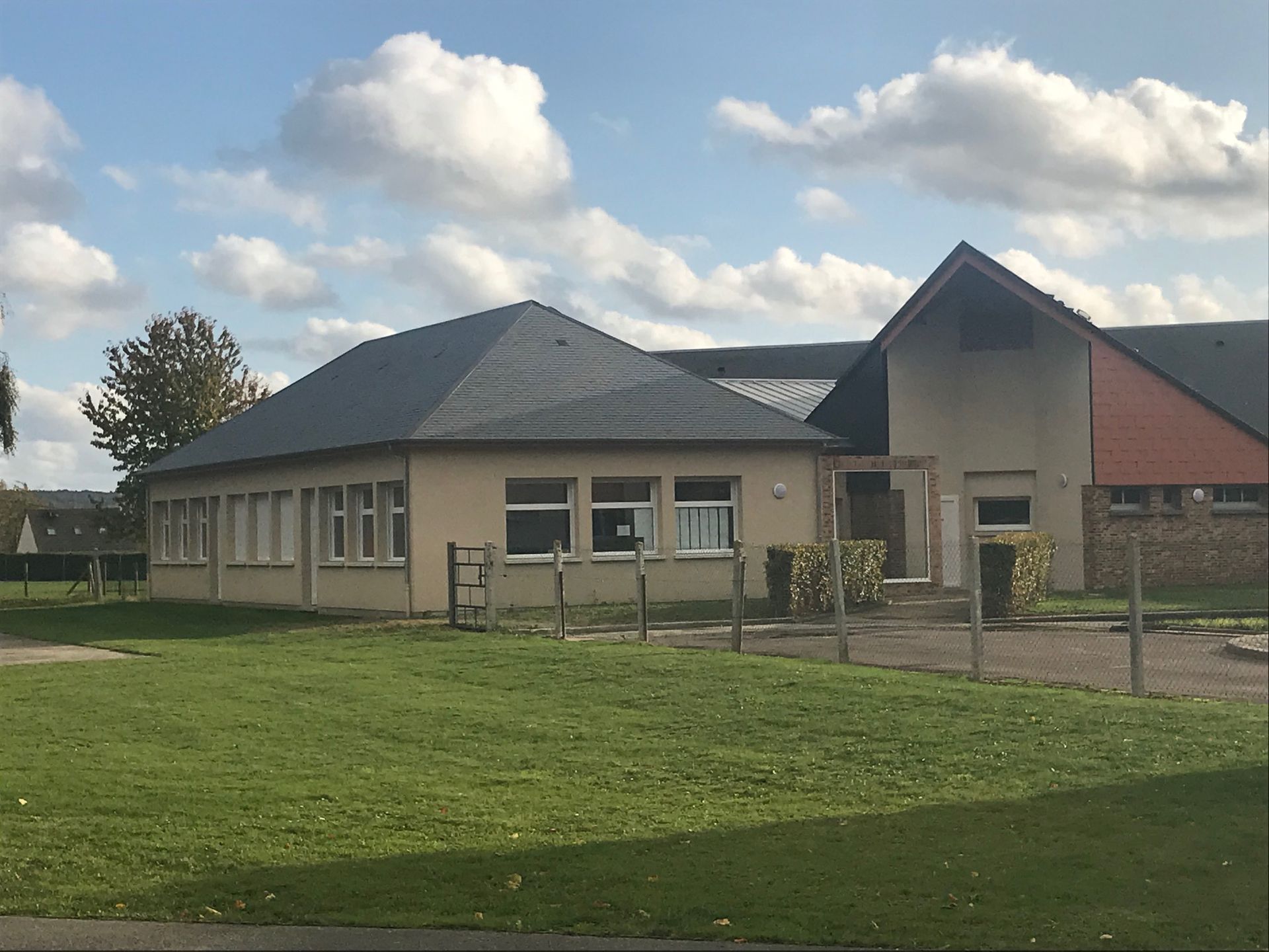 Vue en contre-plongée d'un bâtiment beige au toit et aux fenêtres sombres.