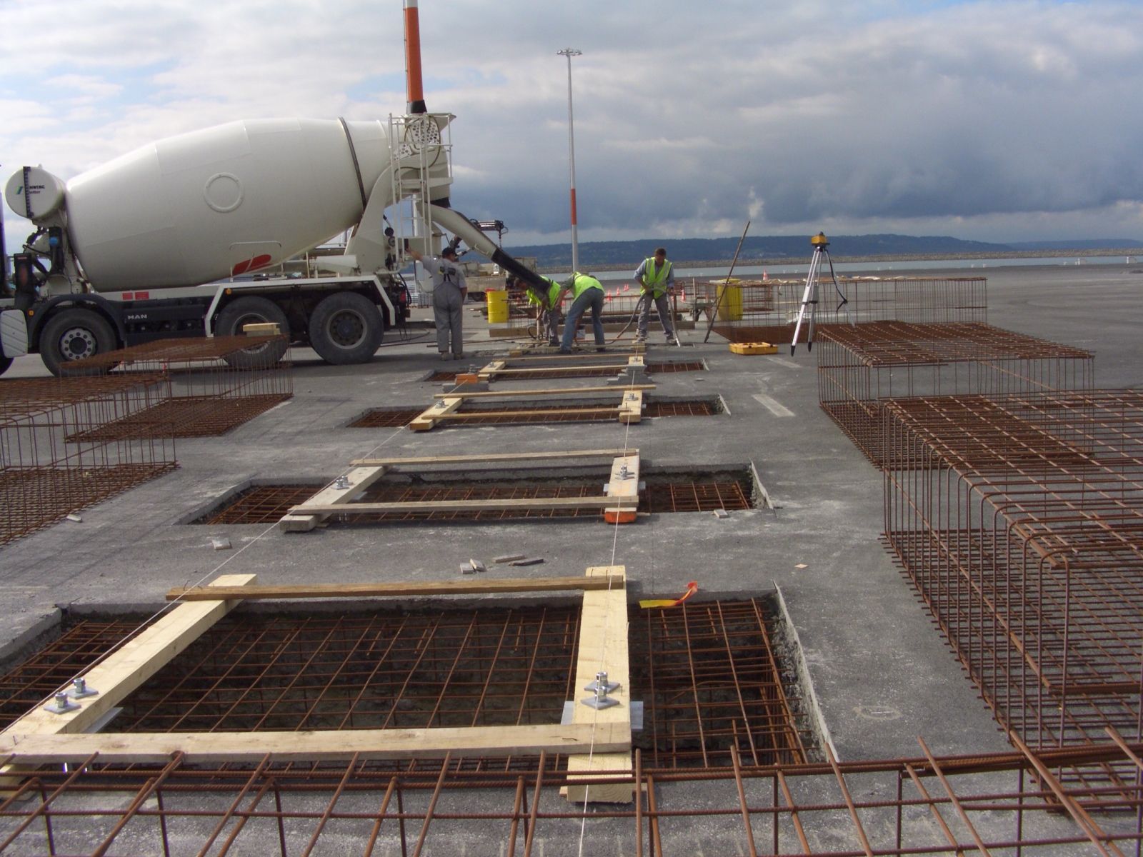 Du béton est coulé sur une dalle armée par un camion-malaxeur sur un chantier de construction.
