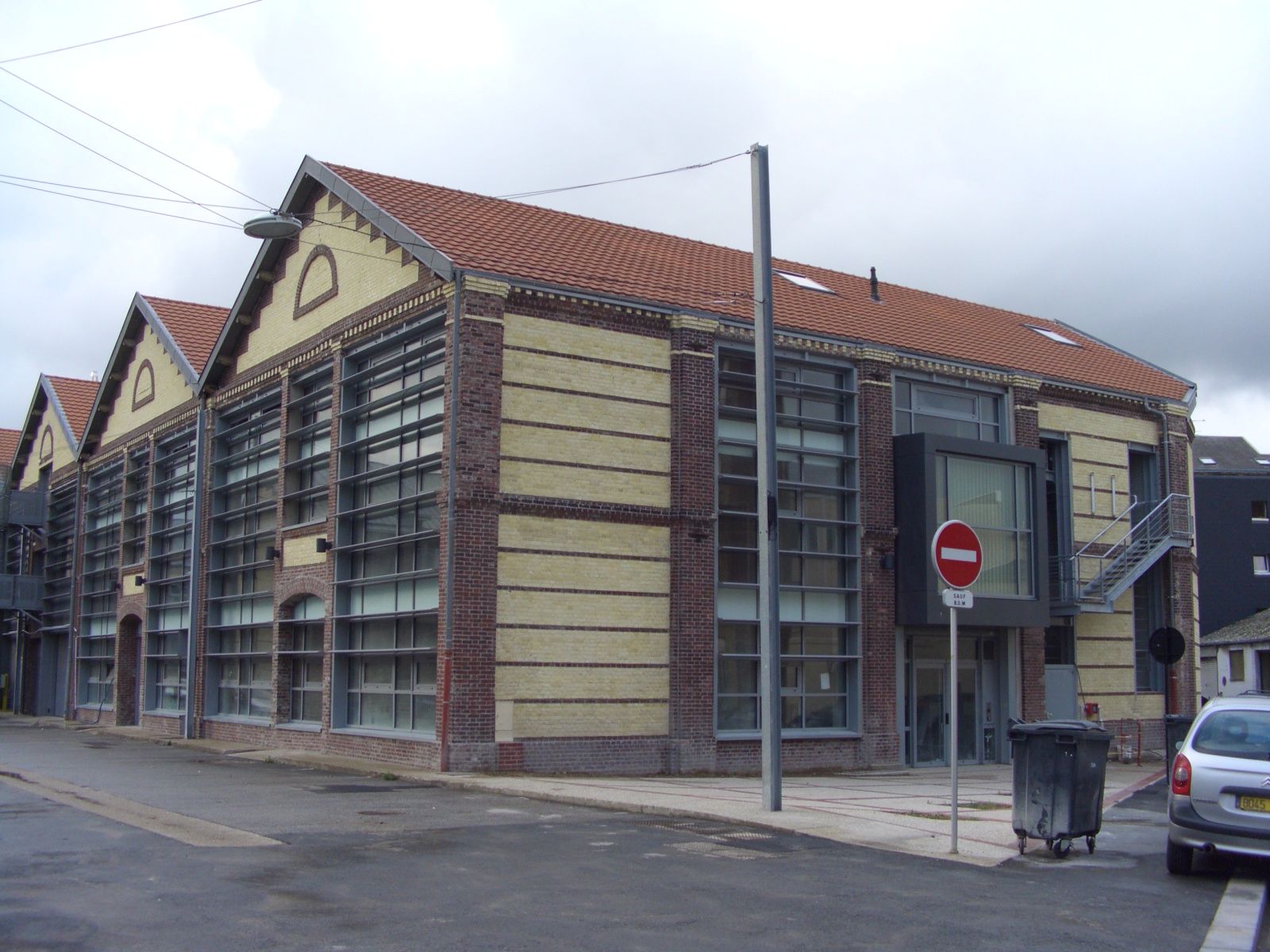 Bâtiment en briques et en verre avec toit de tuiles rouges.