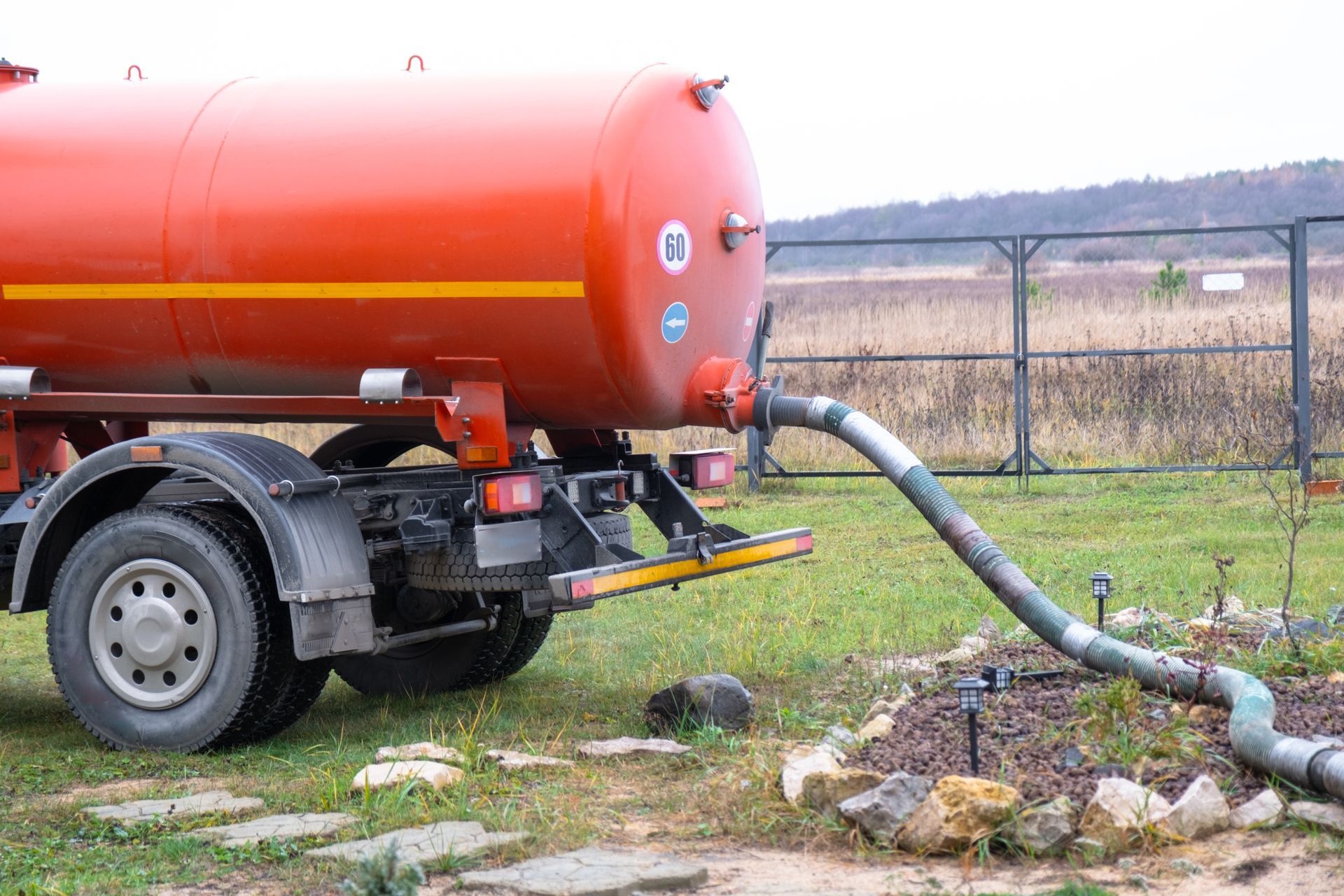 Un camion-citerne orange pompe de l'eau à travers un tuyau dans un champ avec de l'herbe