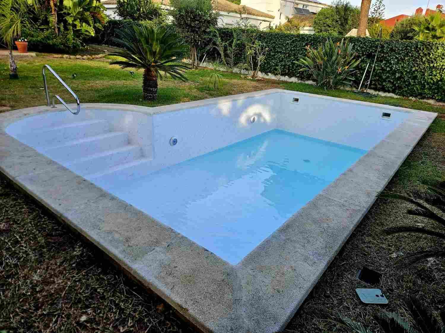 Jacuzzi exterior blanco con escalones y una barandilla metálica en un jardín
