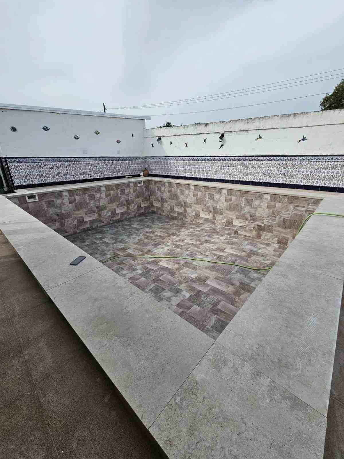 Piscina vacía revestida de azulejos en un patio cerrado en la azotea.