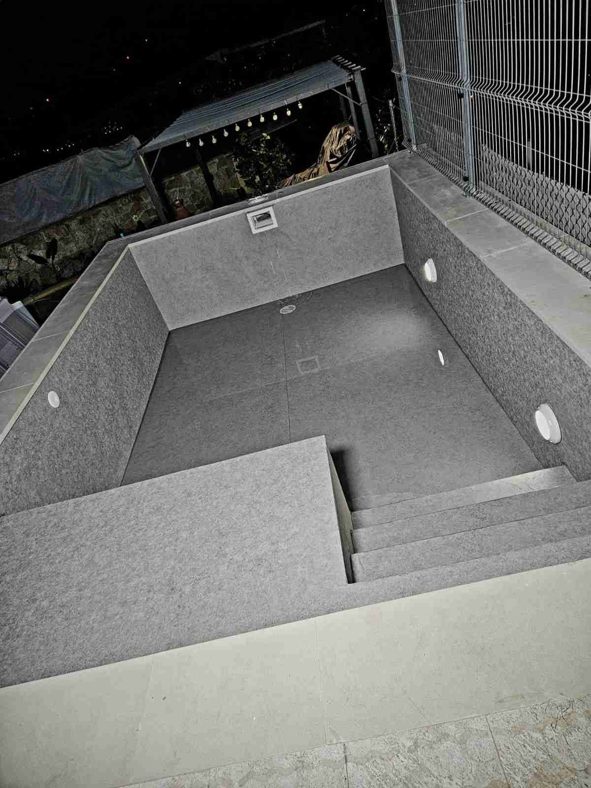 Escalera interior vacía, con paredes y peldaños de hormigón gris, vista desde arriba por la noche