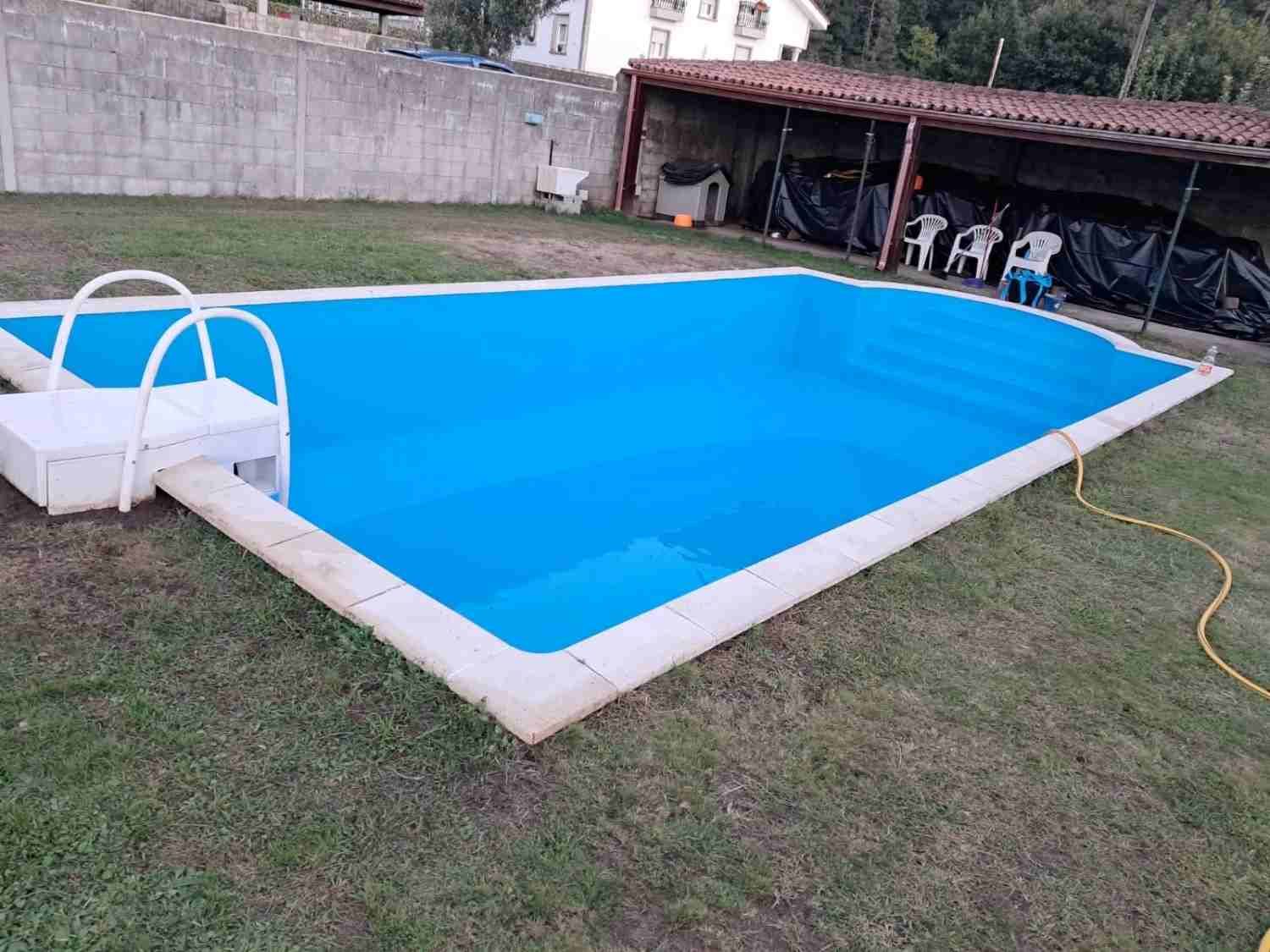 Piscina en el patio trasero con agua azul brillante y una escalera blanca, junto a un patio cubierto y un jardín con césped