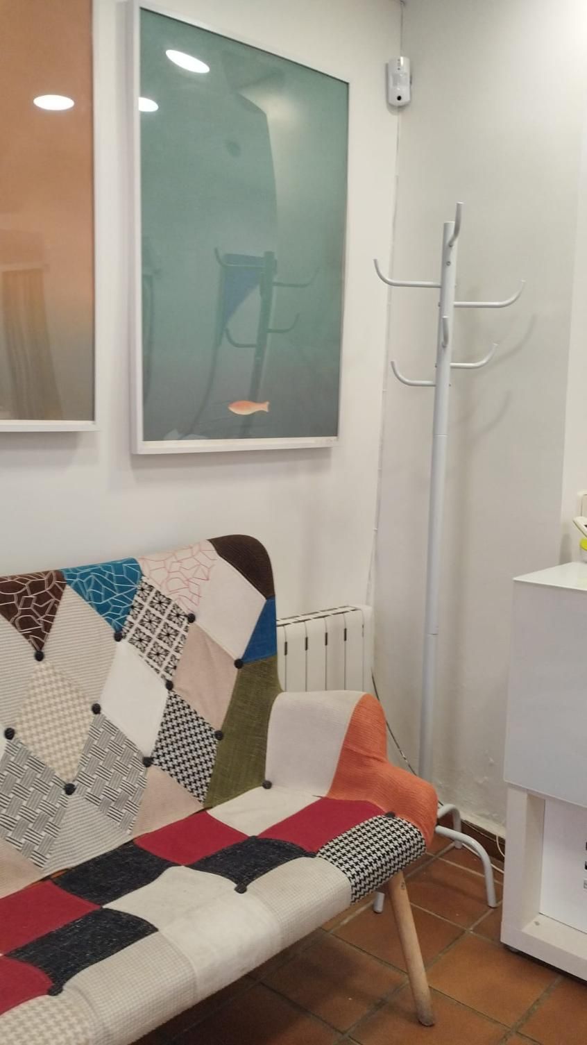 Un sofá de patchwork colorido frente a una pared con arte y un perchero.