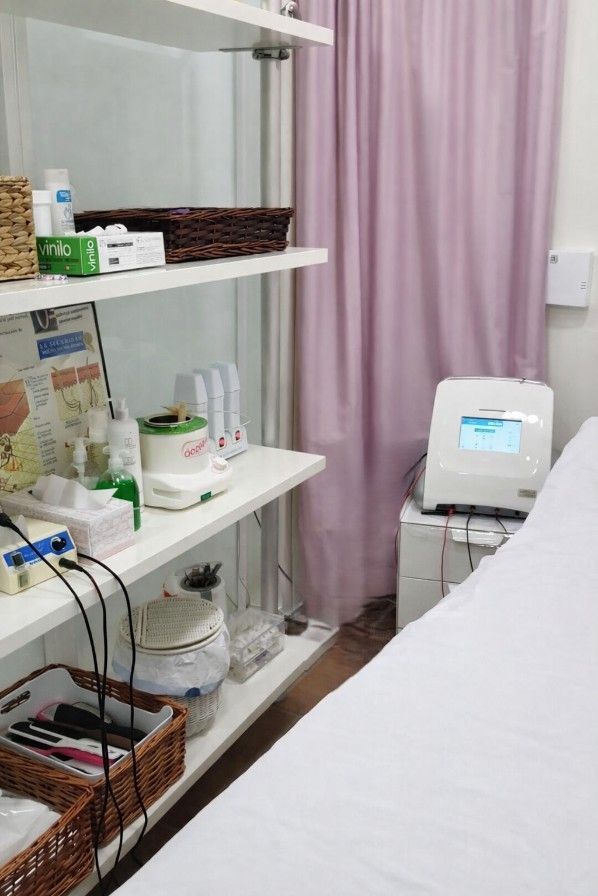 Una pequeña habitación con estantes que contienen suministros junto a una camilla de tratamiento.