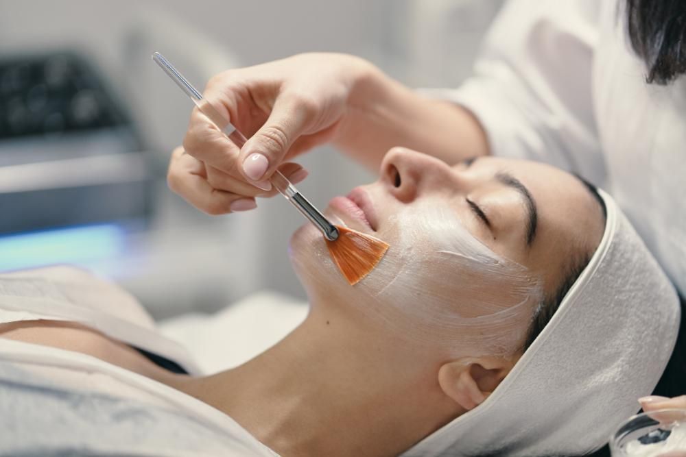 Tratamiento facial: A una persona le aplican una crema en el rostro con un cepillo en un spa.
