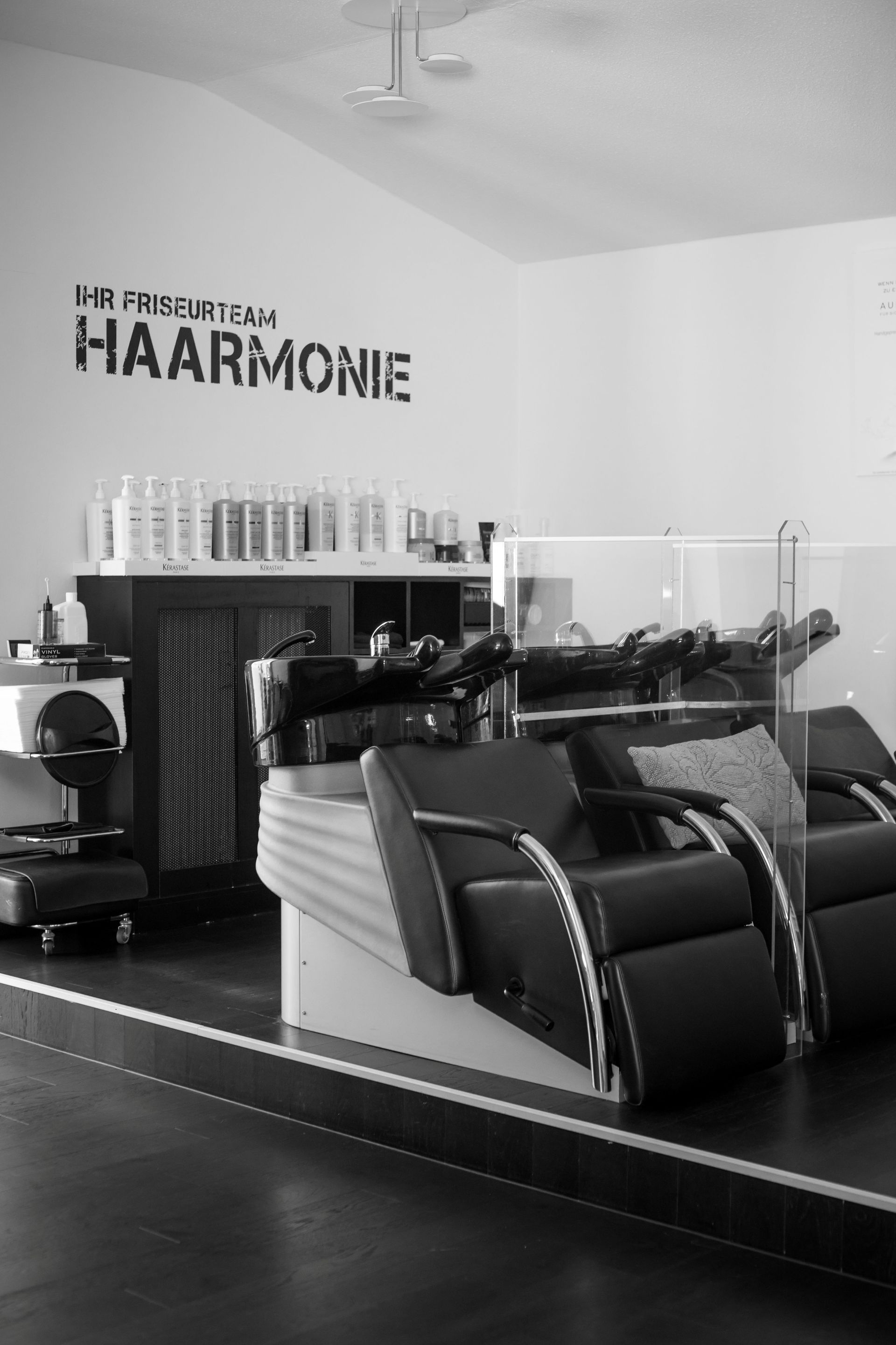 Frau mit langen, gewellten Haaren hält eine Shampoo-Flasche in der Hand und schaut weg.