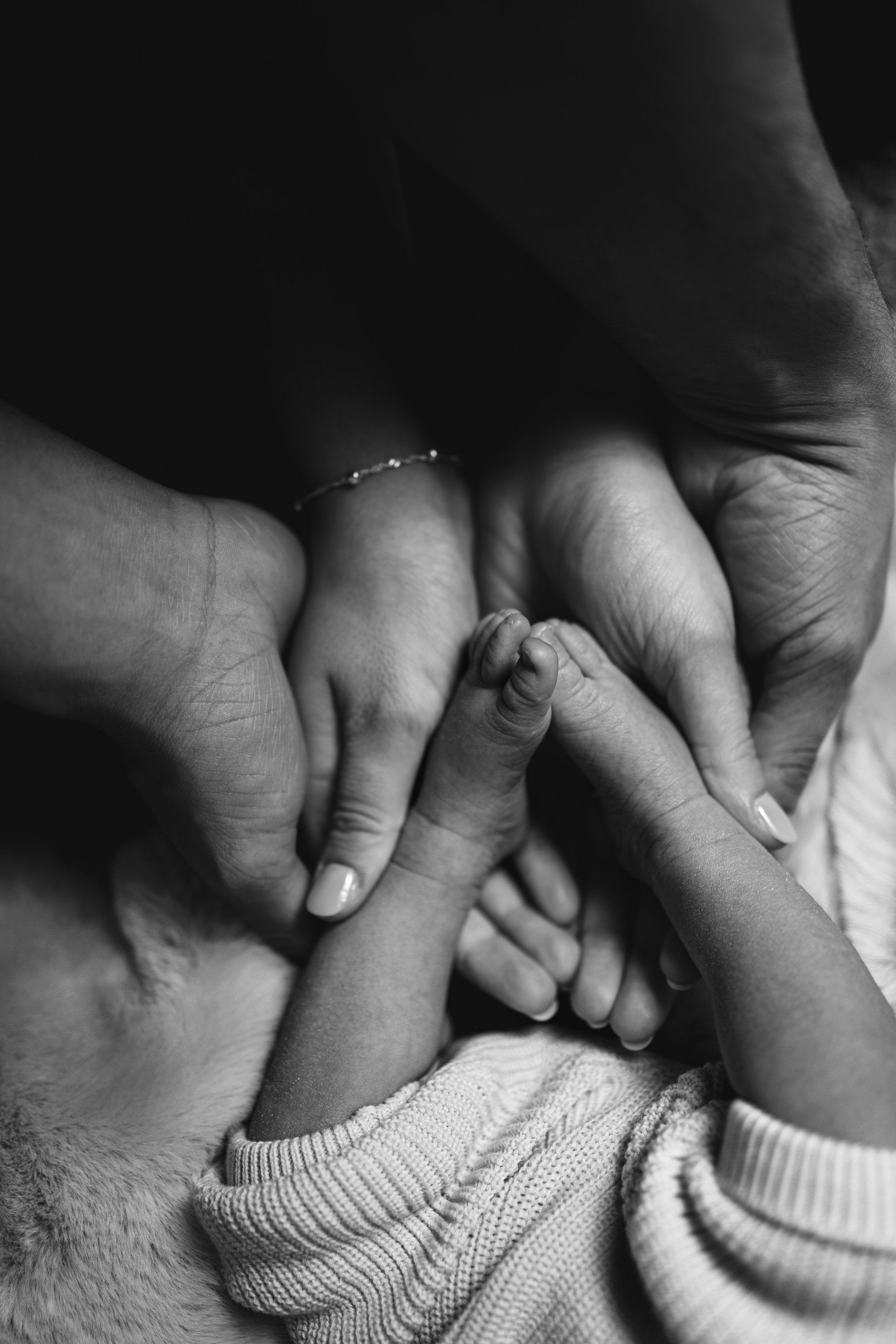 Mains d'enfants et d'adultes jointes en forme de cœur, en noir et blanc.