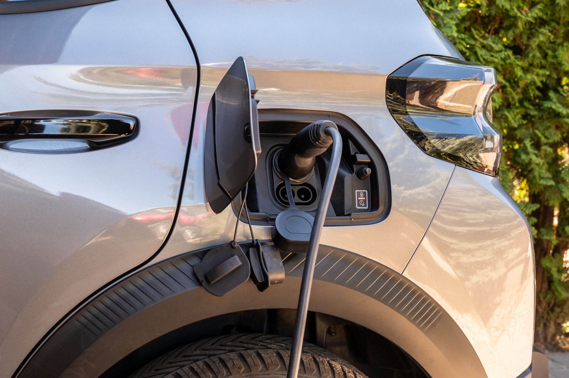 Recharge de voiture électrique avec prise insérée dans le port latéral d'un véhicule argenté