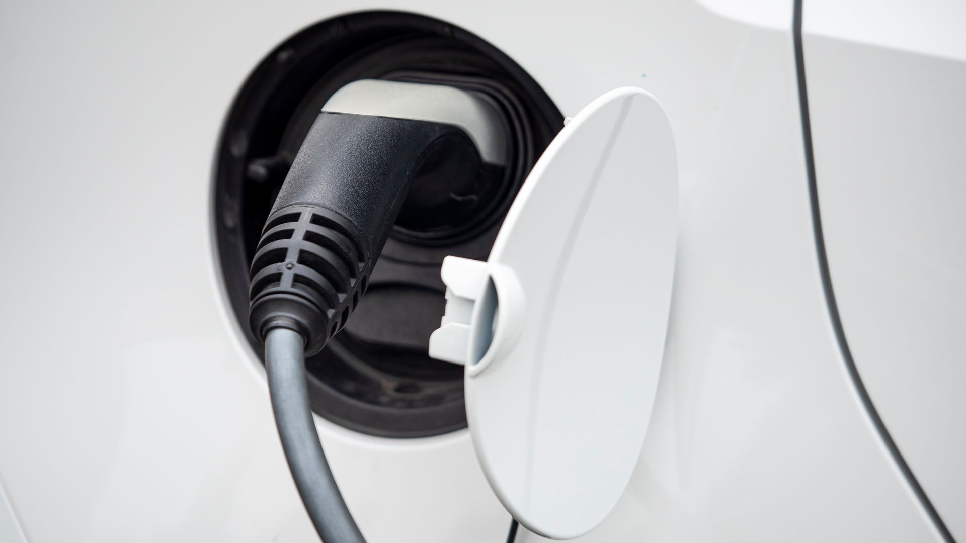 Port de recharge pour voiture électrique avec une prise insérée et le couvercle ouvert.