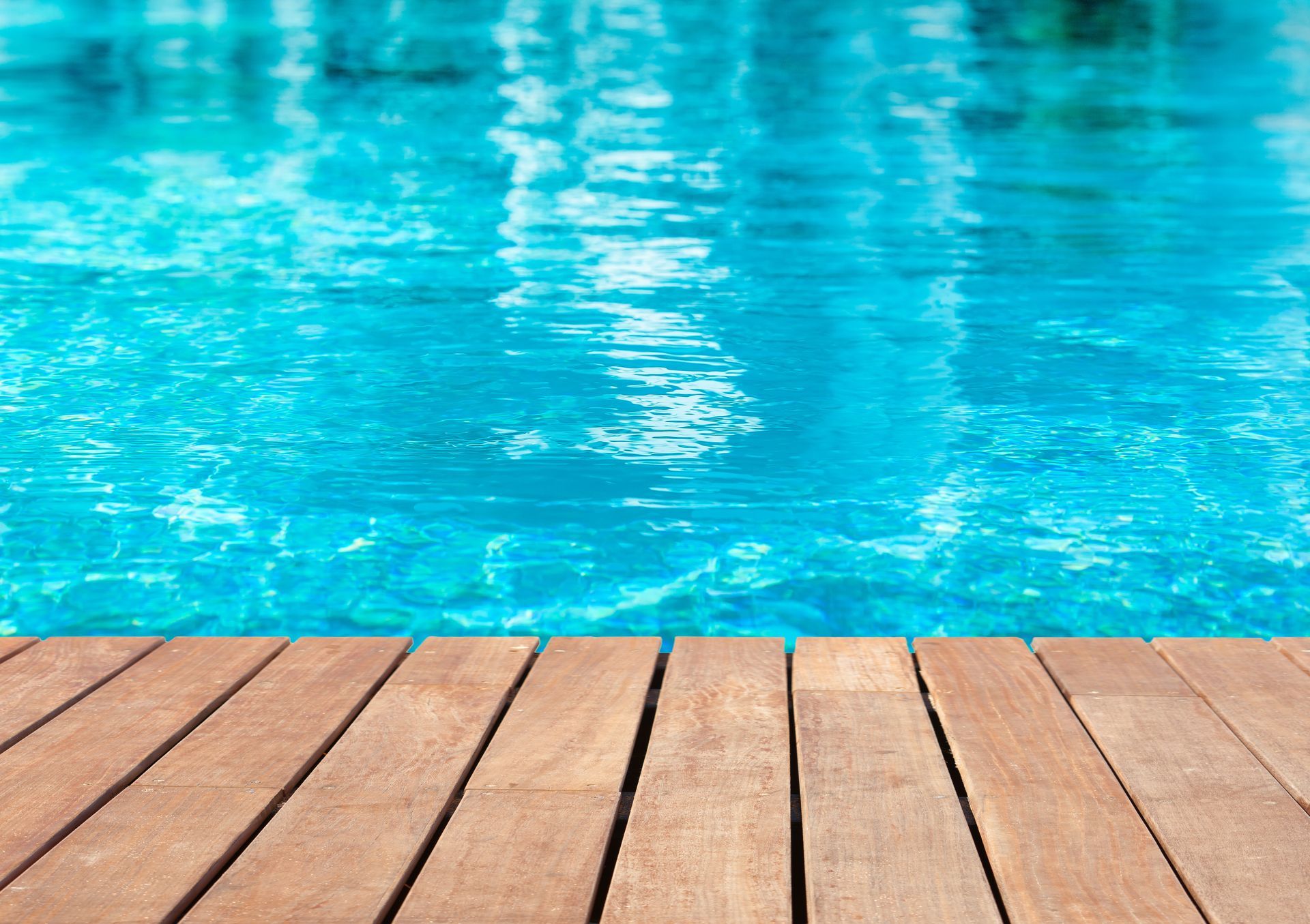 Terrasse en bois au bord au bord d'une piscine.