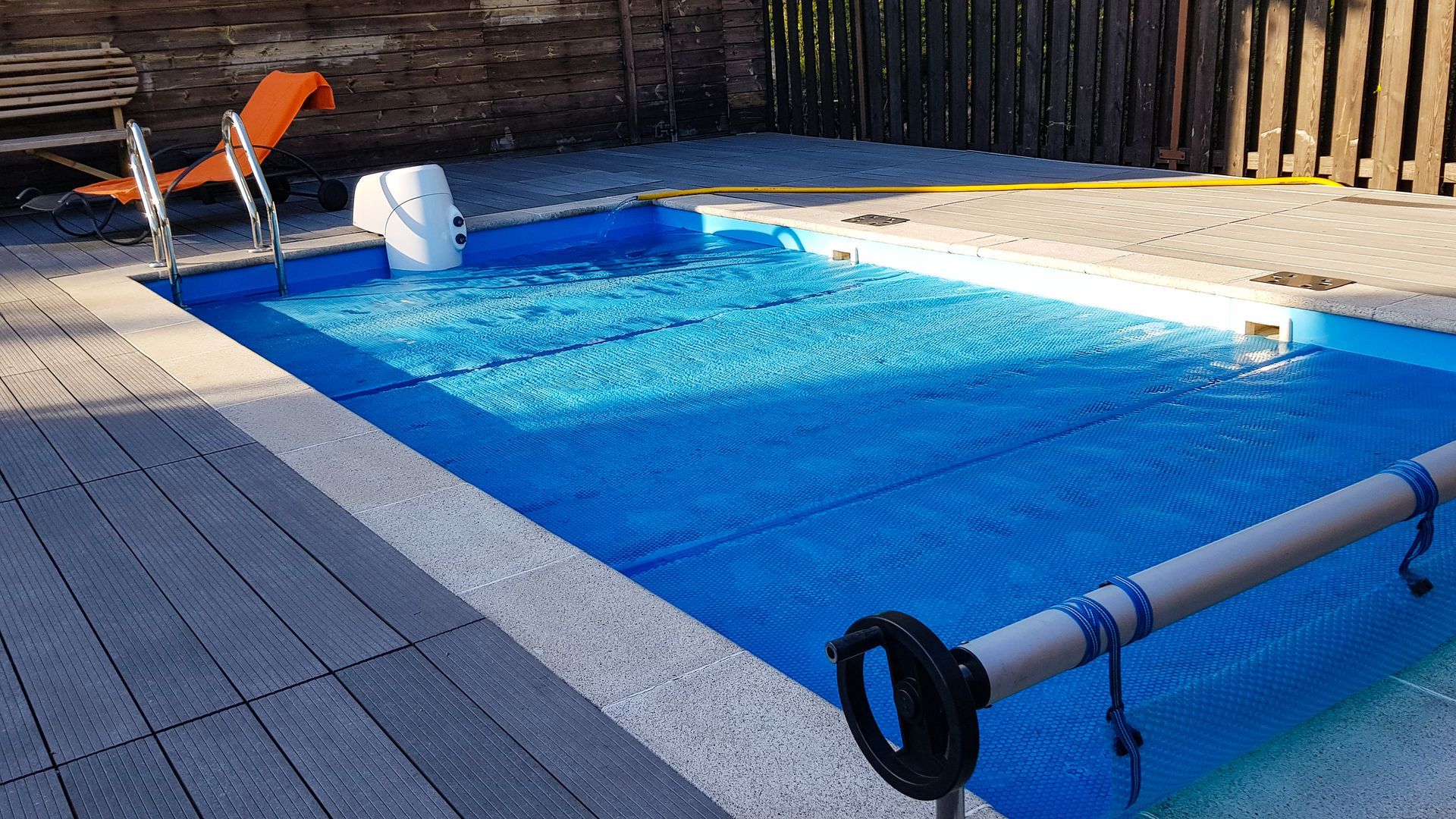 Piscine dans un jardin avec un toboggan orange en arrière plan