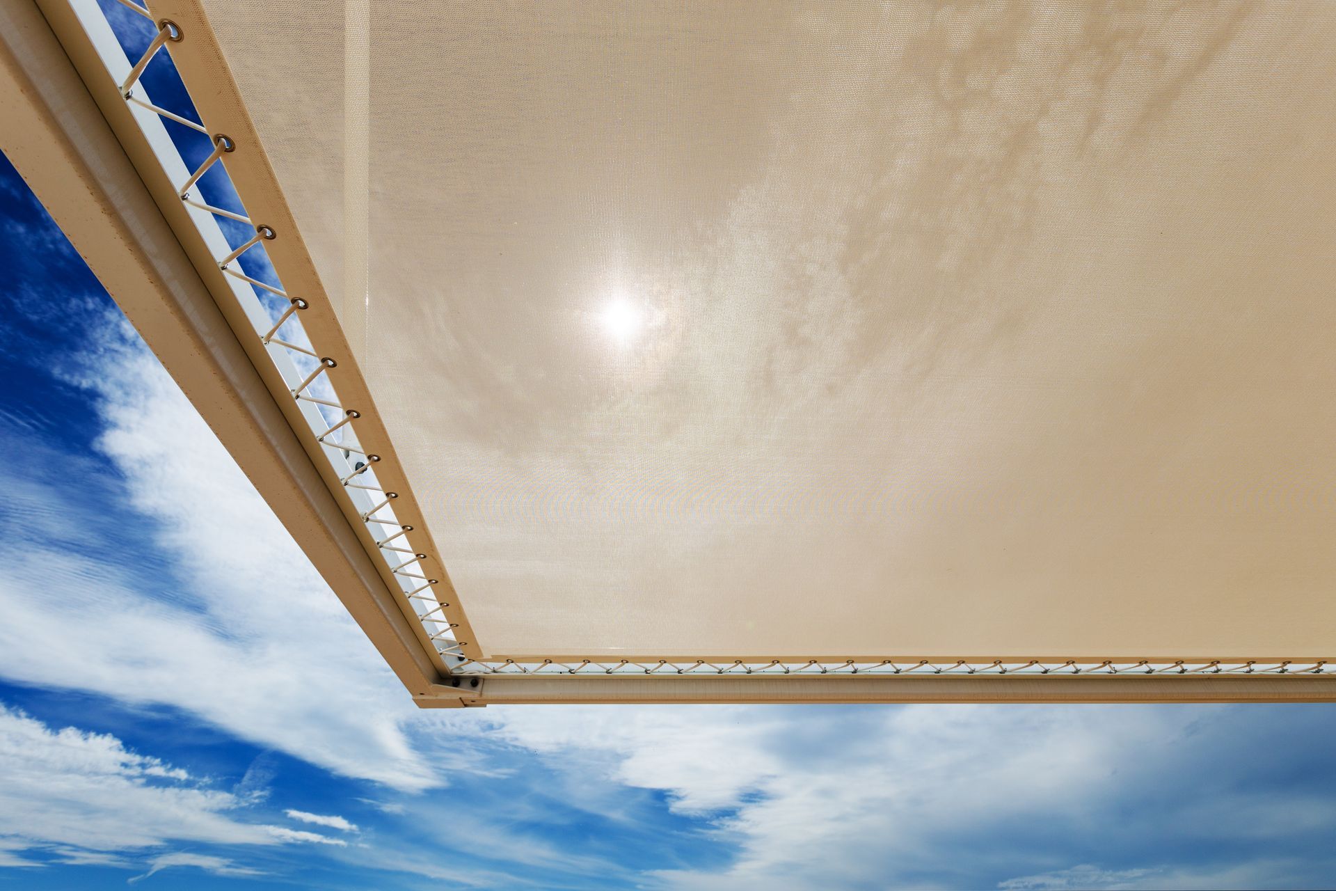 Auvent beige sur un ciel bleu parsemé de nuages blancs