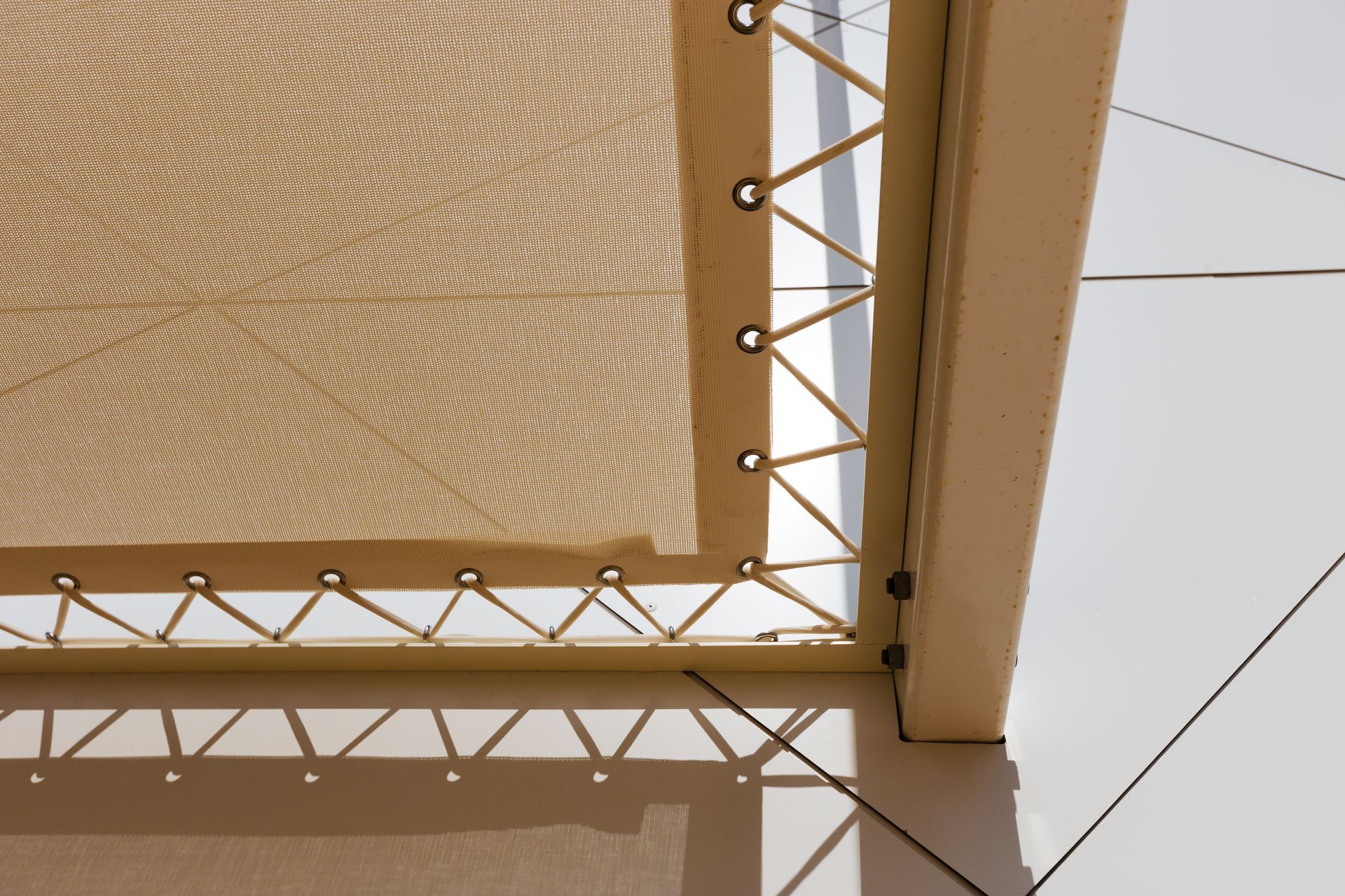 Voile d'ombrage beige avec structure métallique et câbles de soutien